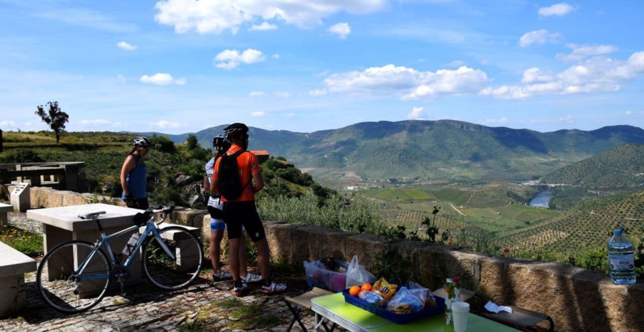 Cyclists enjoying a scenic rest stop with snacks and view of Douro Valley hills